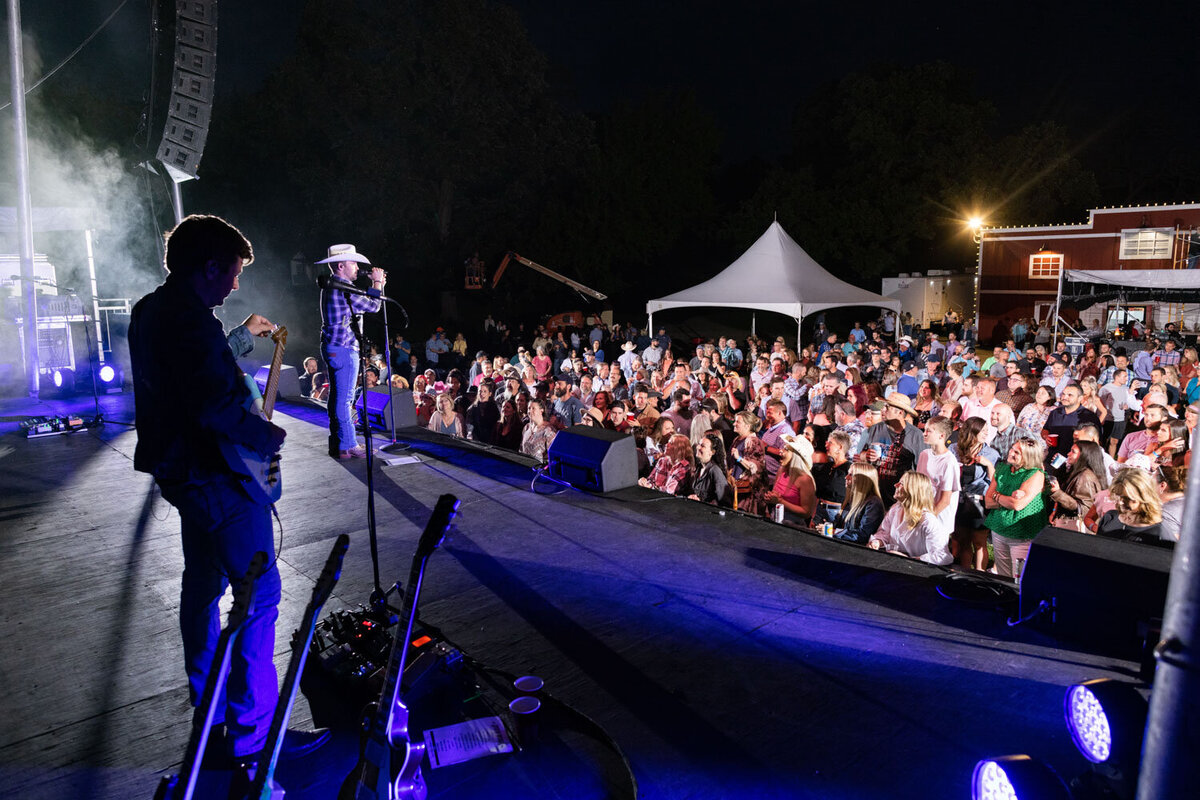 Outdoor concert with a large crowd and stage lighting