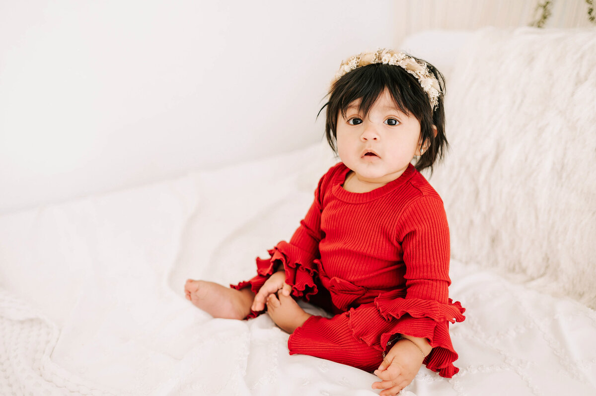 baby photo of girl in red on bed during Branson MO baby milestone session