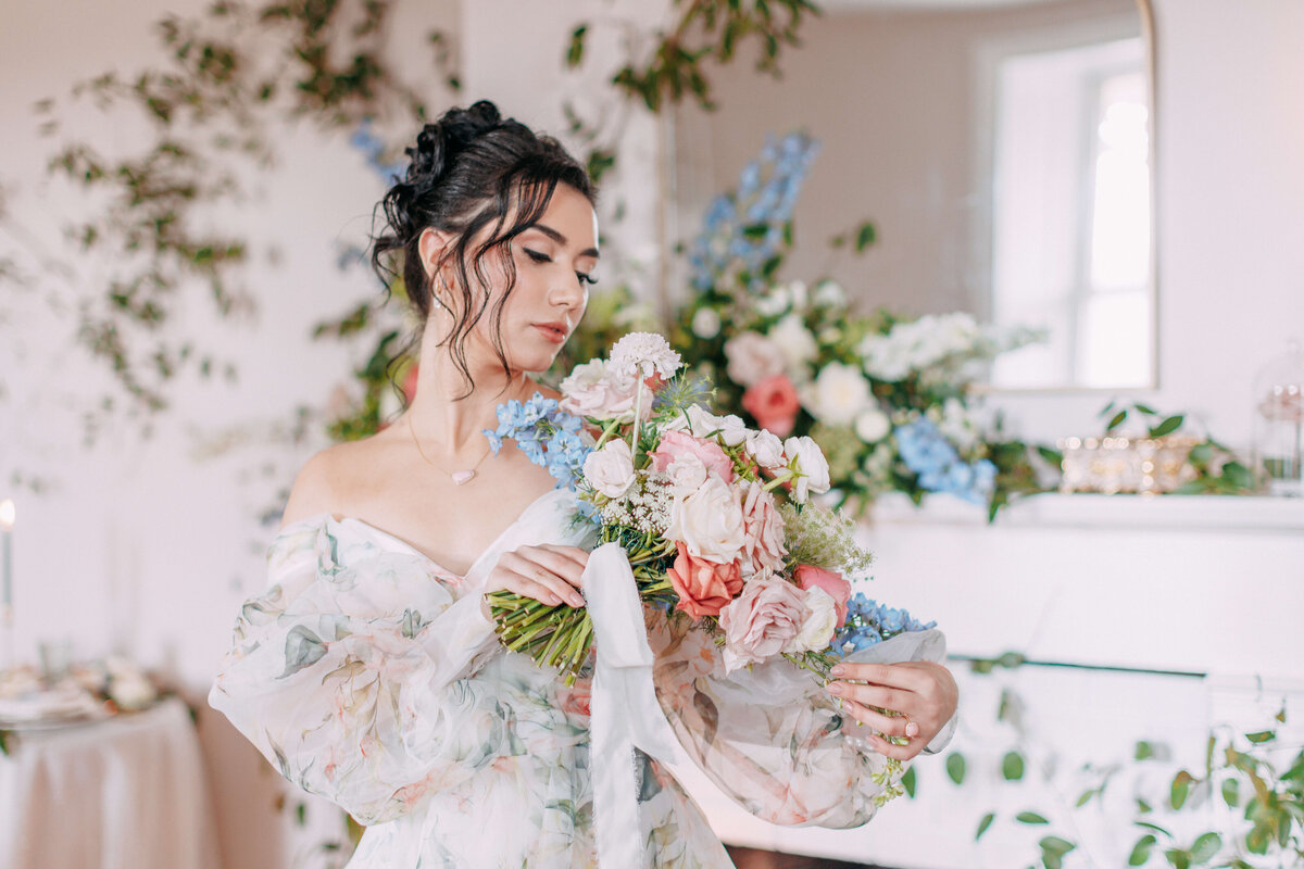 bride holding bouquet of blue, peach and pink florals