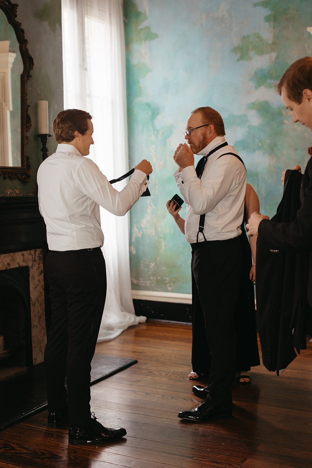 dad and groom learn to tie a bow tie
