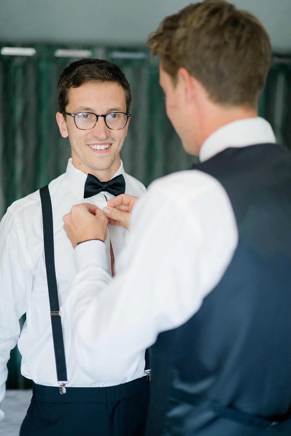 Columbus wedding  photographer captures groom getting ready with his best man as he helps with his bow tie