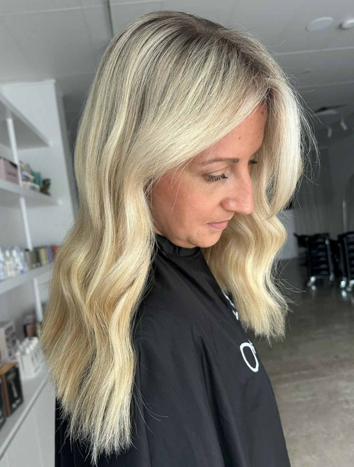 Sandy blonde haired aomen in black hairdresser cape