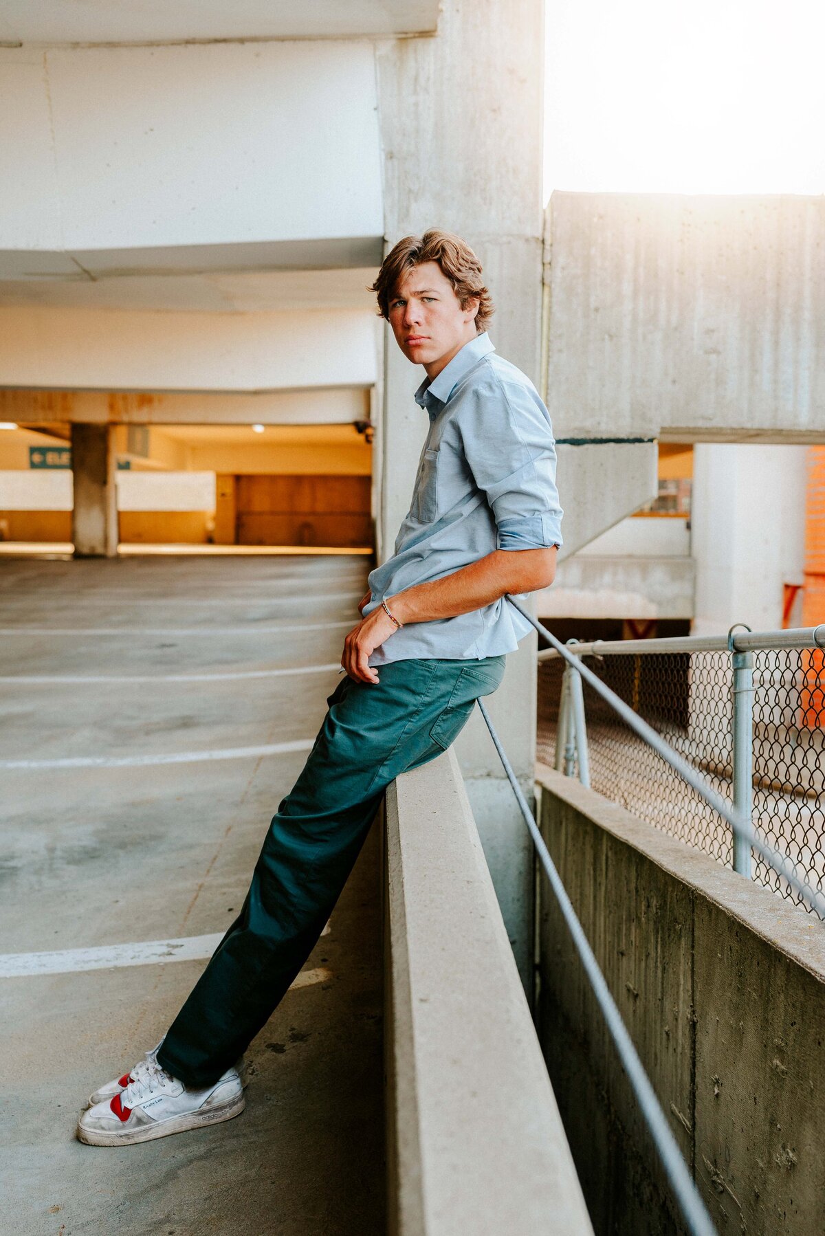 In the heart of Minneapolis, this striking senior portrait features an Edina High School graduate leaning confidently against a railing on a downtown parking garage. With leading lines creating a dramatic perspective, he gazes directly into the camera, capturing the essence of a young graduate ready to embrace the city's opportunities.