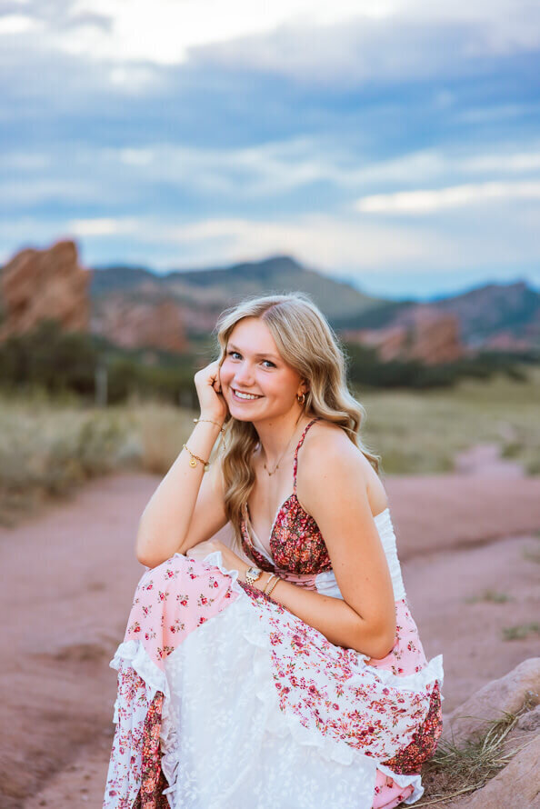 Girl poses in front of red rocks with her head in hands.