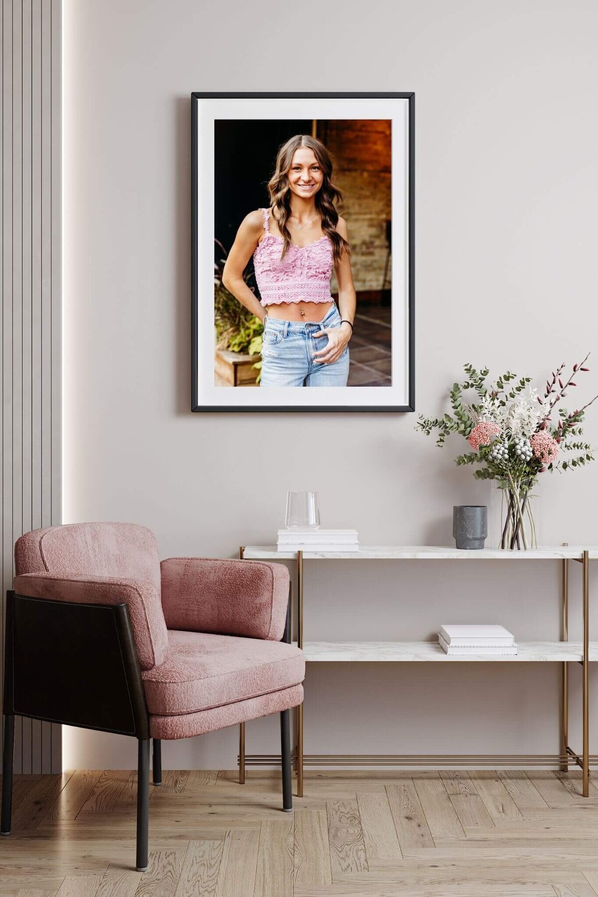image of a high school senior girl framed and matted and hung above a pink chair in a home near Neenah.