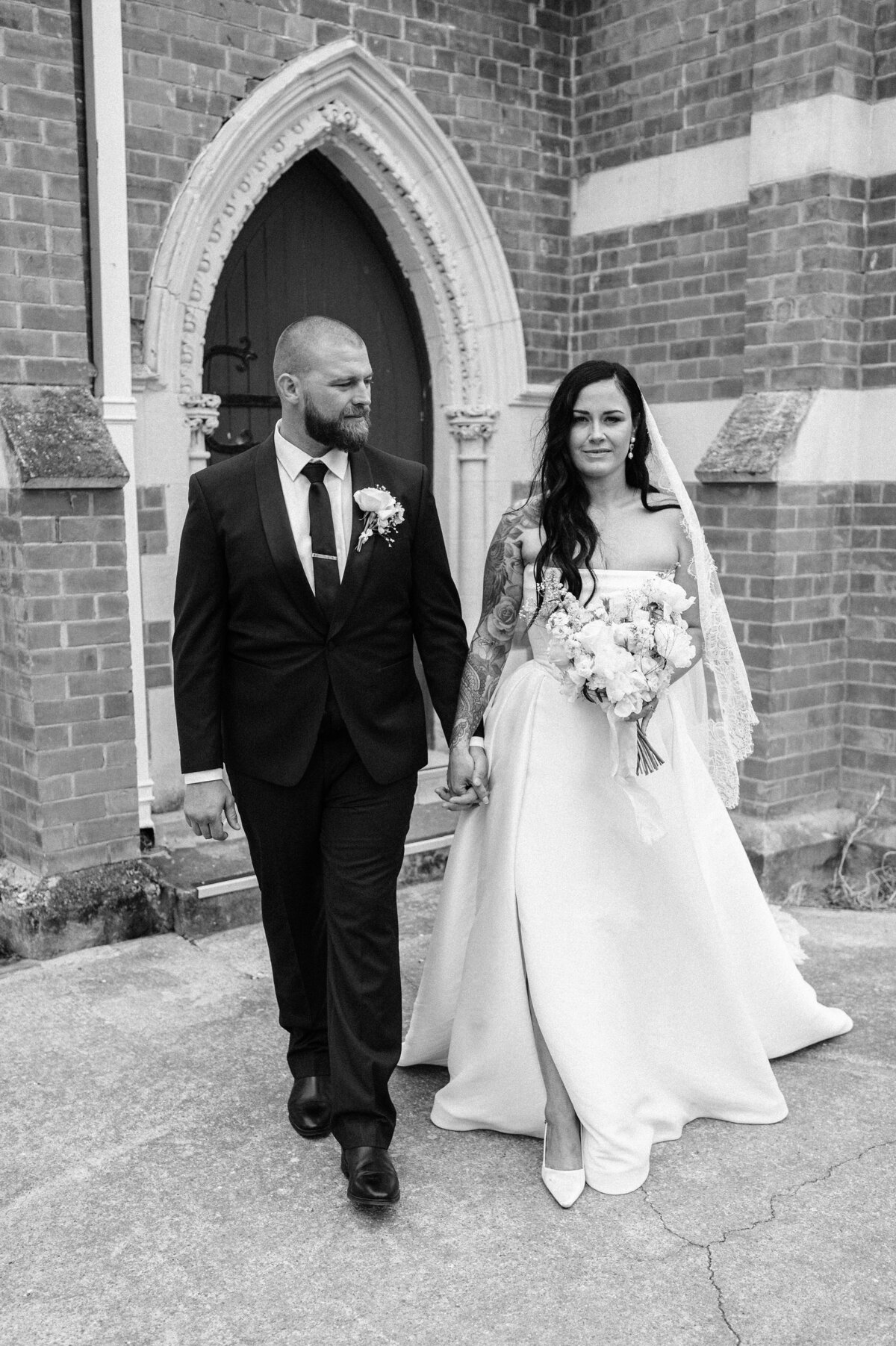 elegant editorial style image of a bride and groom walking out of a church near christchurch
