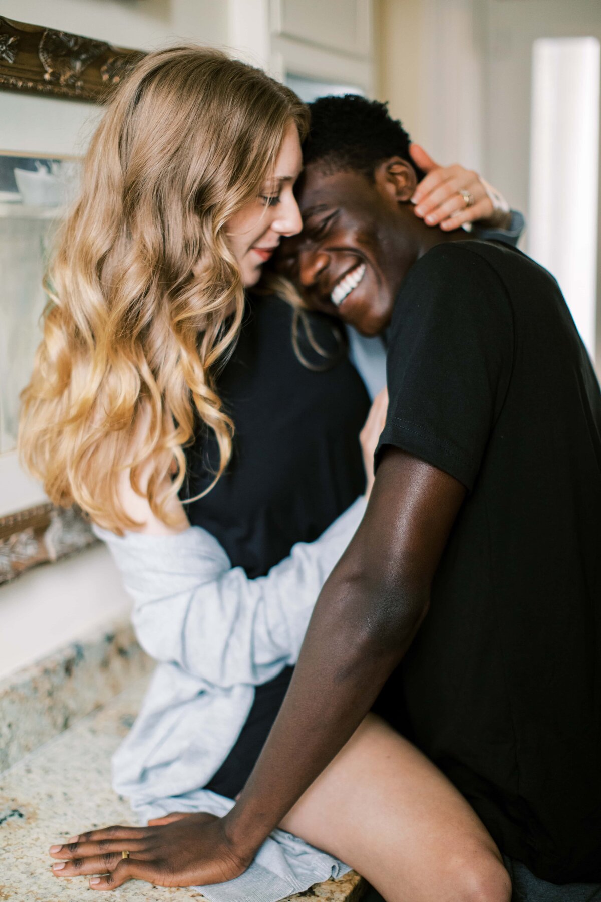 Emotional engagement photo of cute interracial couple snuggling on kitchen counter of home in Charleston, South Carolina by Danielle Defayette