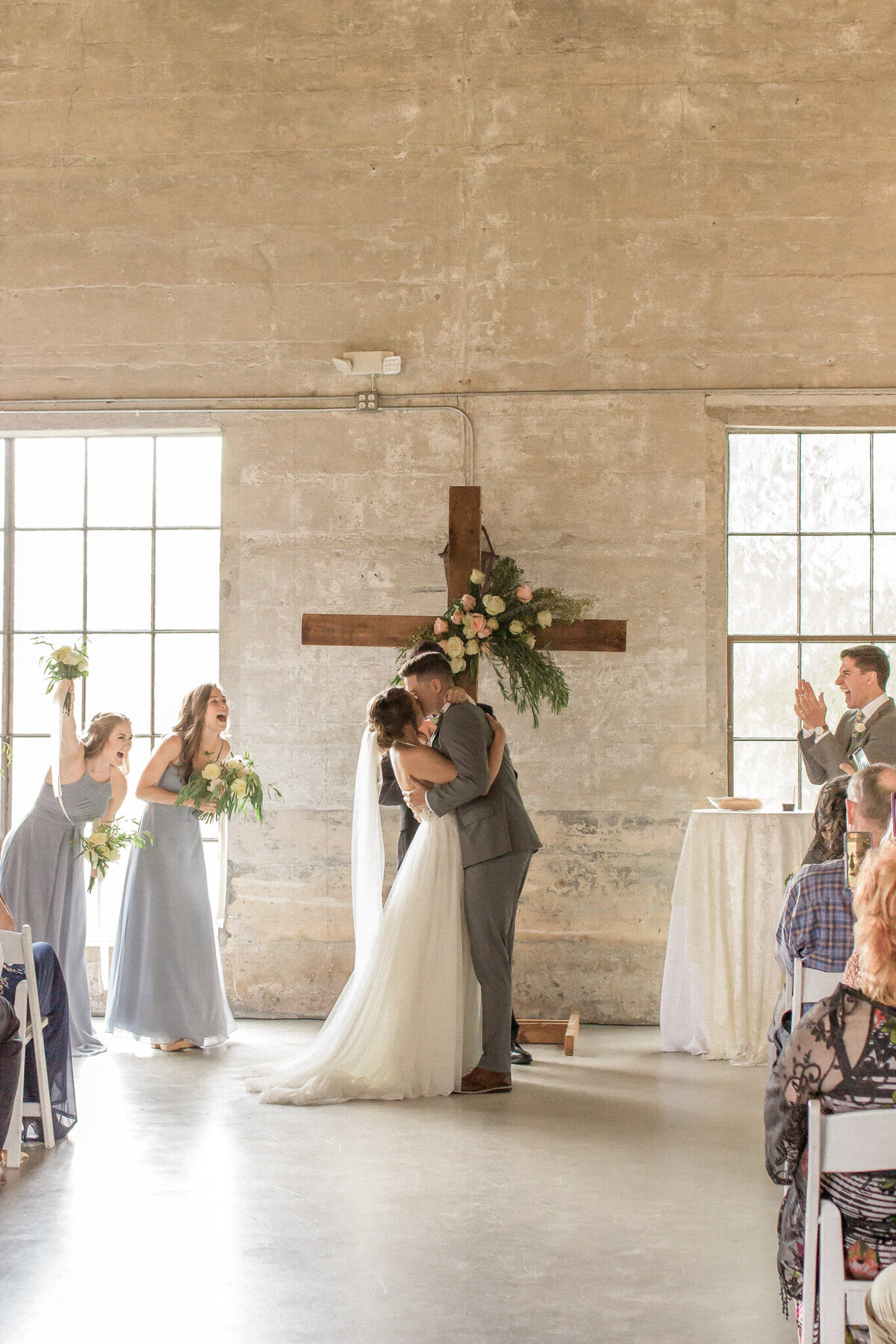 The wedding party celebrates as the bride and groom kiss for the first time as husband and wife.