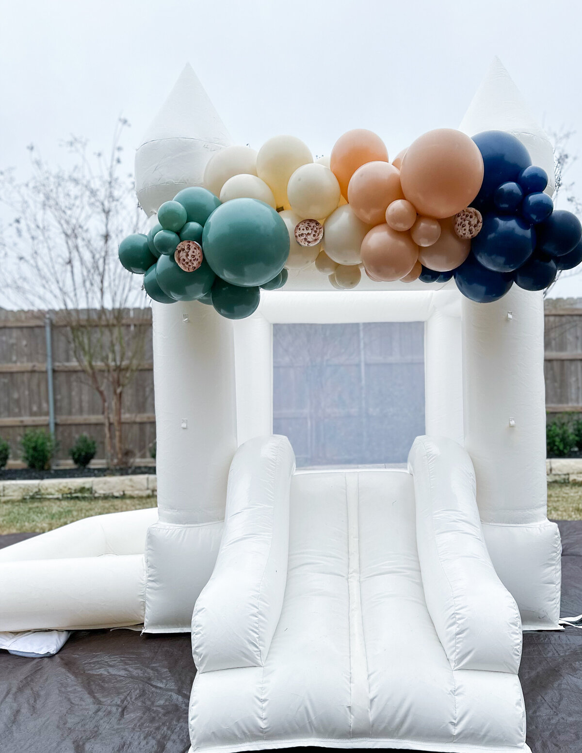 Balloons on a small white bounce house with cookie cutouts. 