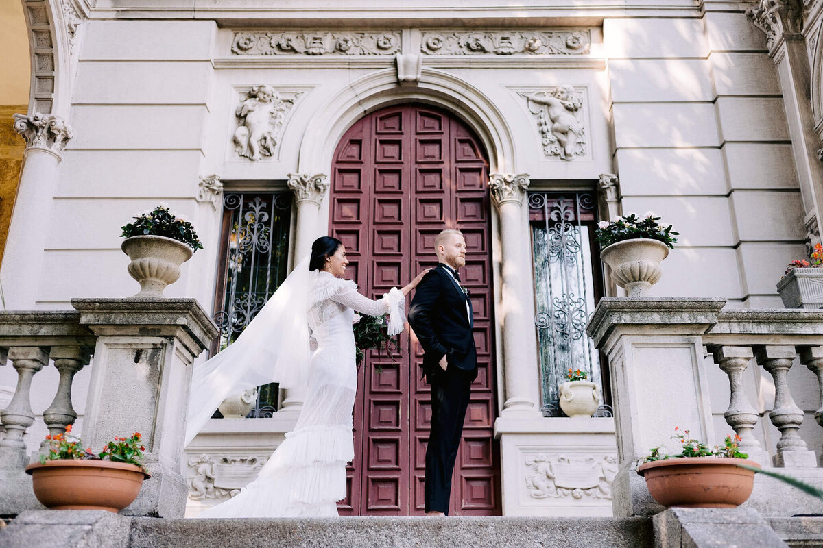Side view shot of a bride holding on the back of the groom, in the entrance of a vintage villa