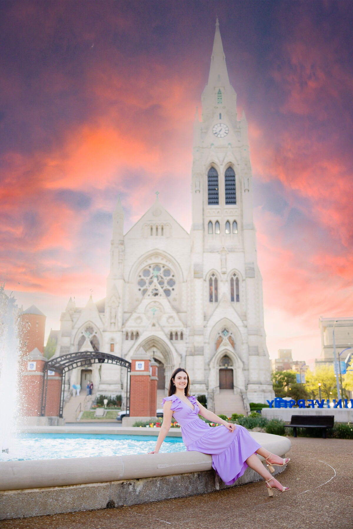 senior girl sitting in SLU fountain with St. Francis Xavier church in the background