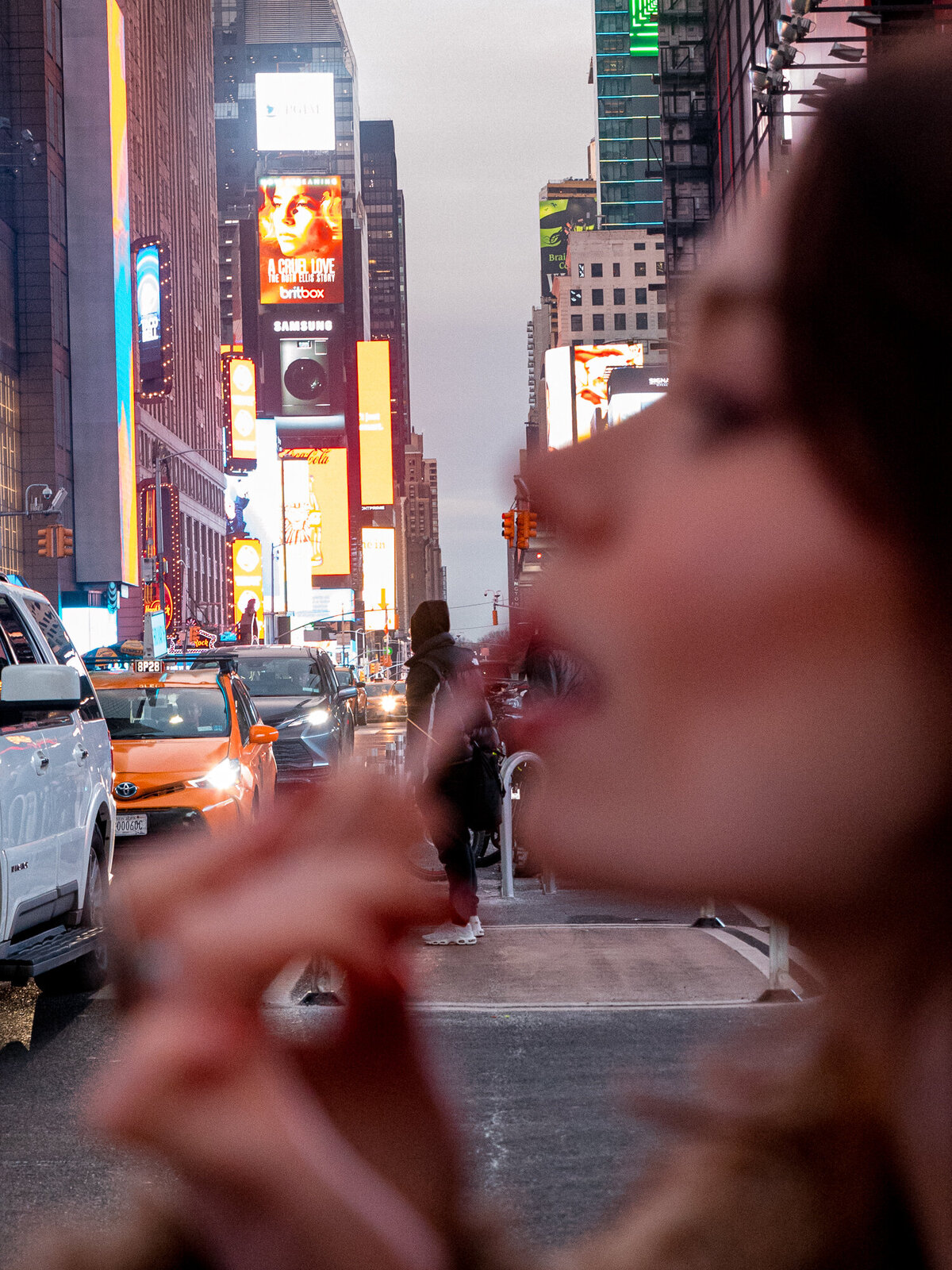 Times Square in focus behind blurred girl putting on lip gloss