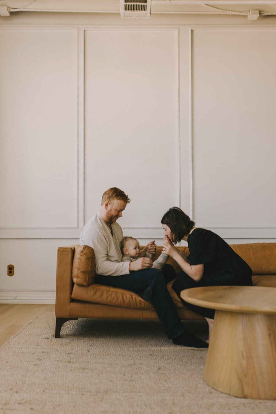 mom dad and baby sitting on a couch