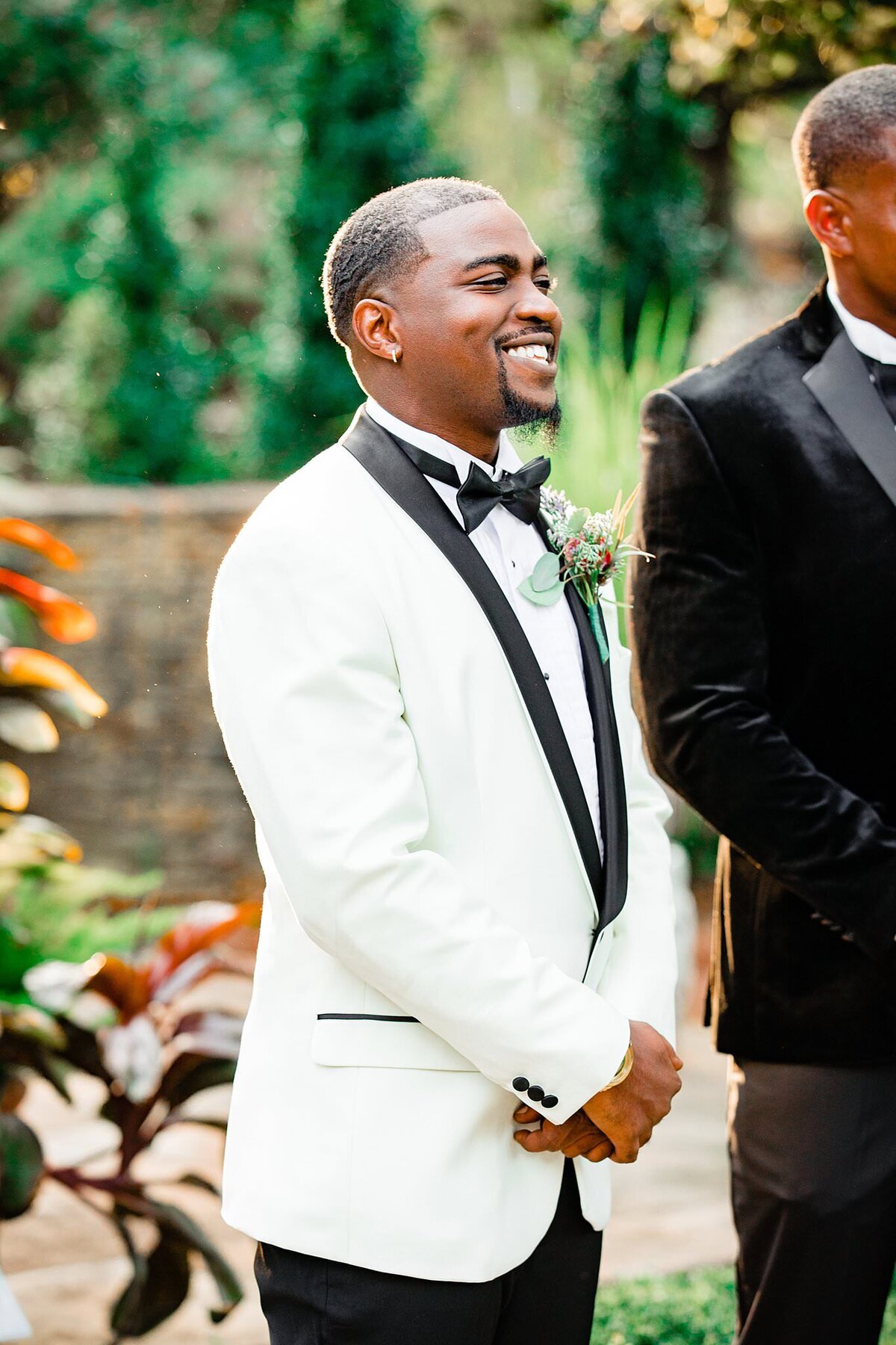 Groom seeing his wife coming down the aisle for the ceremony, he is wearing a white jacket with black detailing