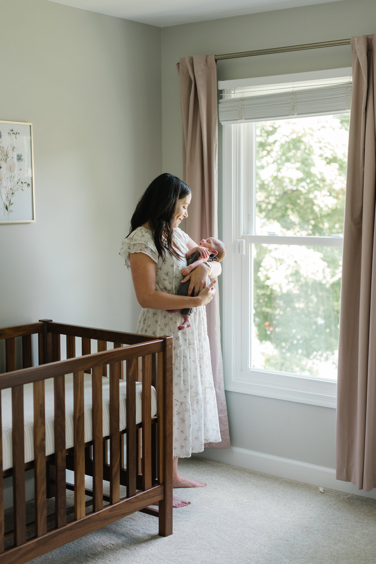 Mother holding her baby in a nursery by the window