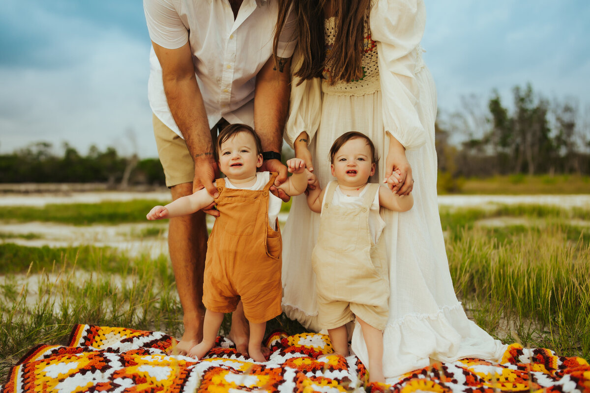 twin boys standing on a 70's blanket at the beach