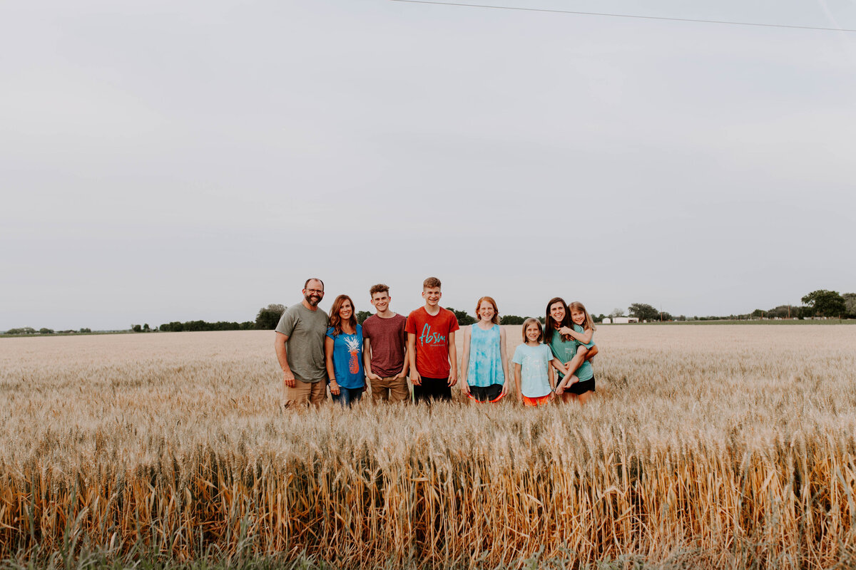 family of 8 standing in field smiling