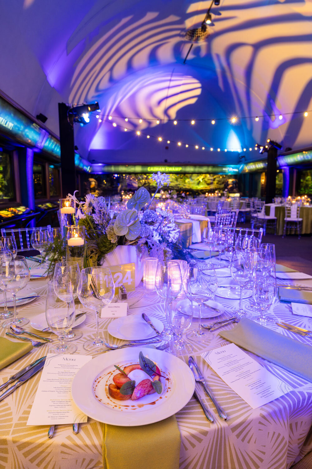 Candlelit wedding reception table under blue and purple lighting.