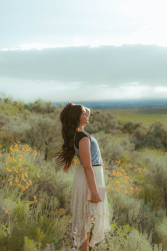 Standing in a field of sagebrush in Rexburg, Idaho, a woman looks off into the distance during a photography session for her missionary photos.