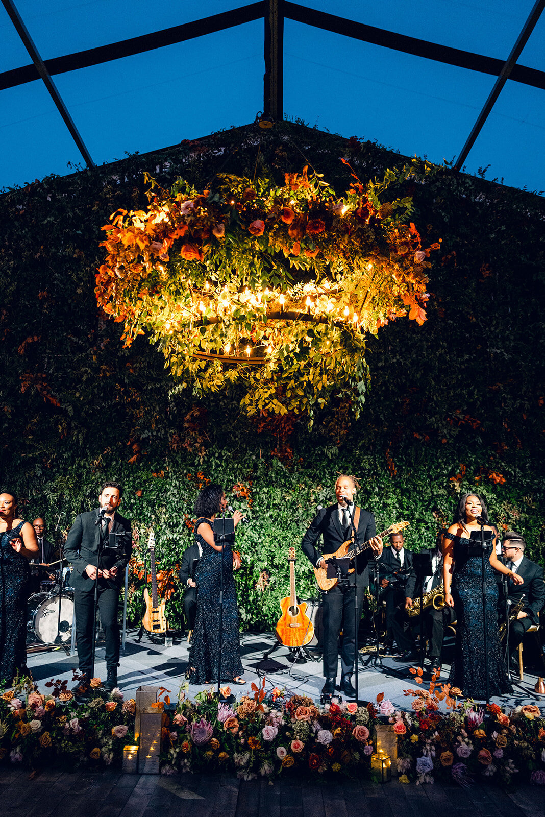 Large hoop chandelier decorated with fall florals for wedding reception. Black rimmed clear tent wedding reception on Tennessee hilltop. Private home wedding ceremony and reception on hilltop. Destination floral design for wedding ceremony and reception florals. Fall florals consisting of roses, protea, dahlias, mums, and fall branches. Design by Rosemary & Finch Floral Design in Nashville, TN.