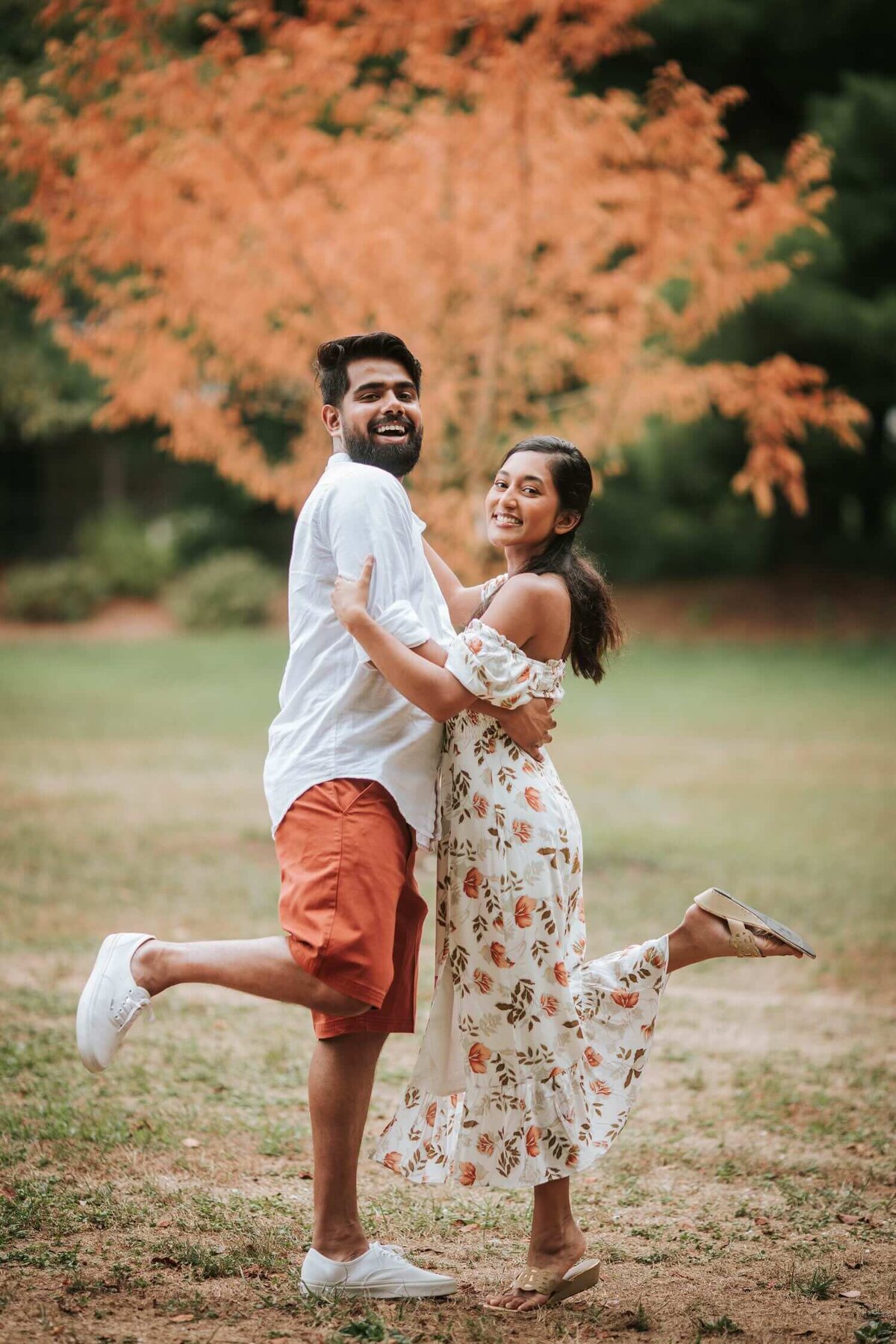 South Asian Couple embracing each other outside with one leg in the air in New Jersey.