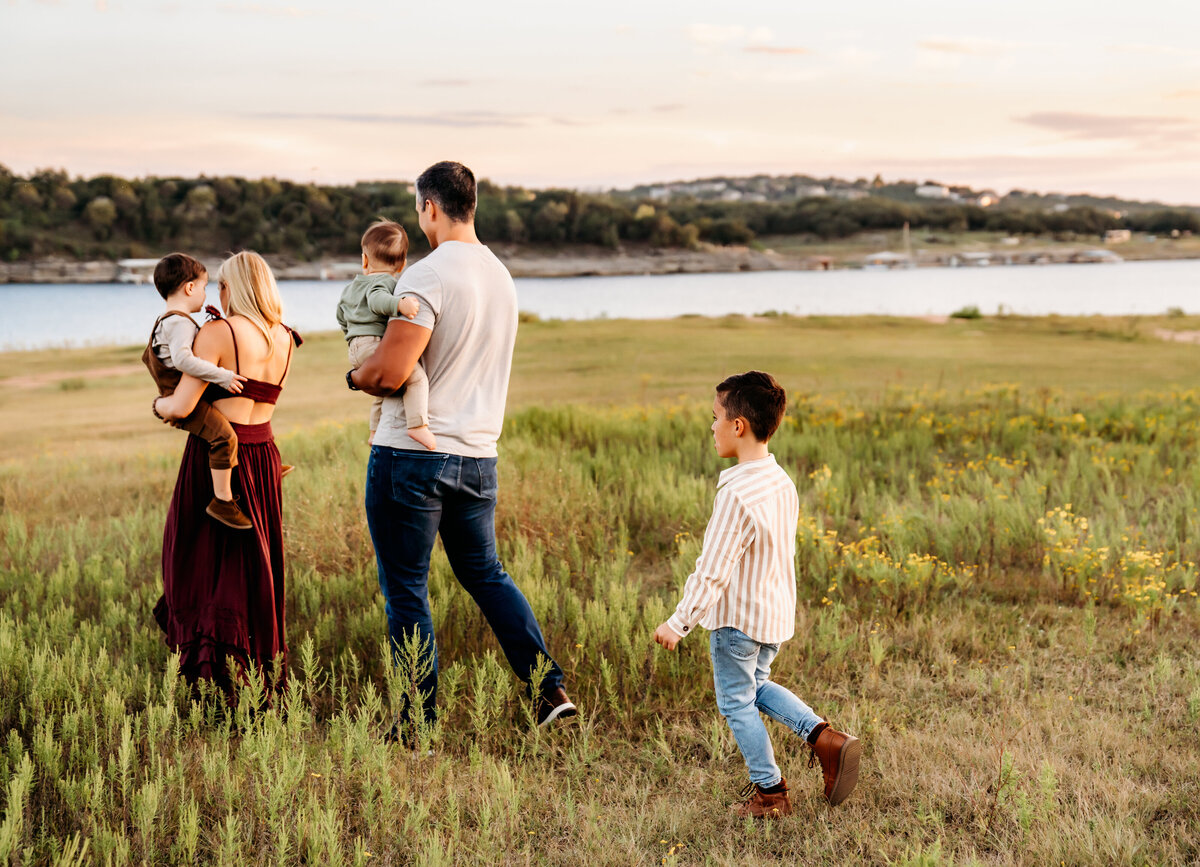 Family Photographer, a family walks through the grass toward the lake