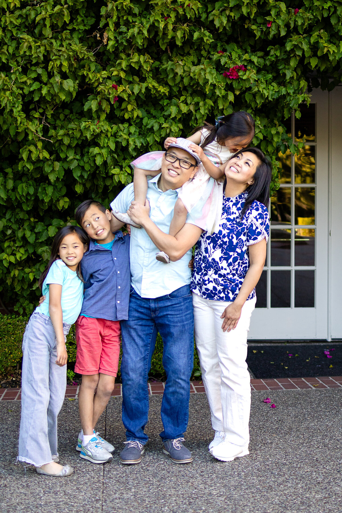 Golden hour portrait of a family of five standing down in rose garden – joyful, natural light family photography by Ellobelle Photography in the San Francisco Peninsula kohl mansion Burlingame