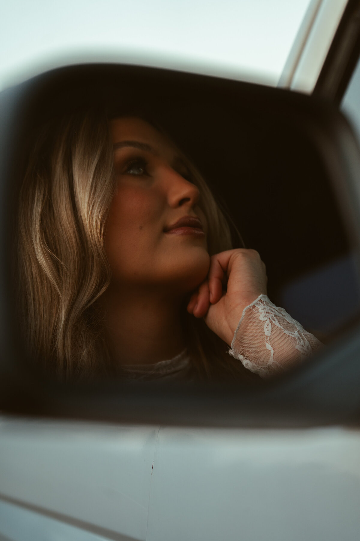 Girl captured through a Bronco mirror—moody, reflective portrait with soft lace details and a dreamy, film-inspired tone.