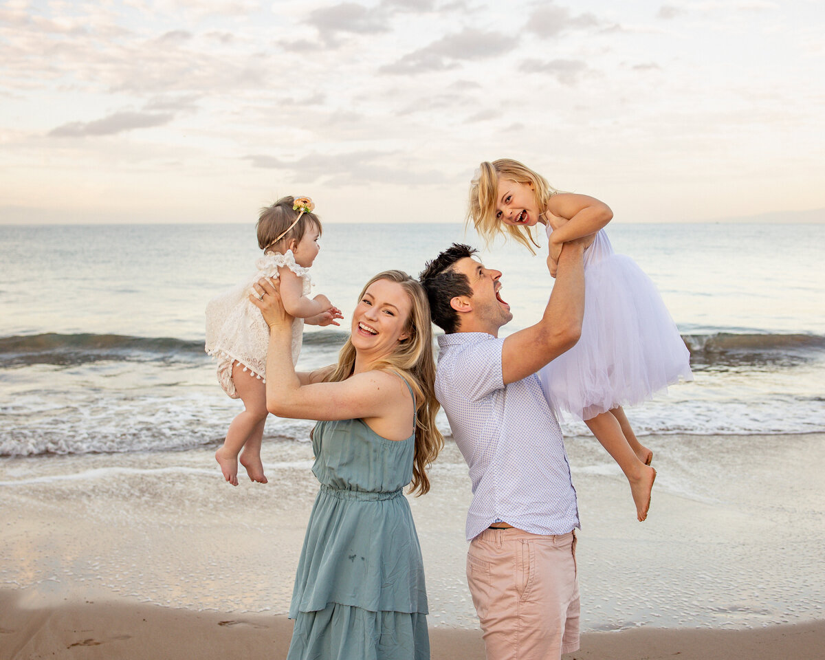 Maui Family Photographers capture parents lifting daughters in air during beach family photos