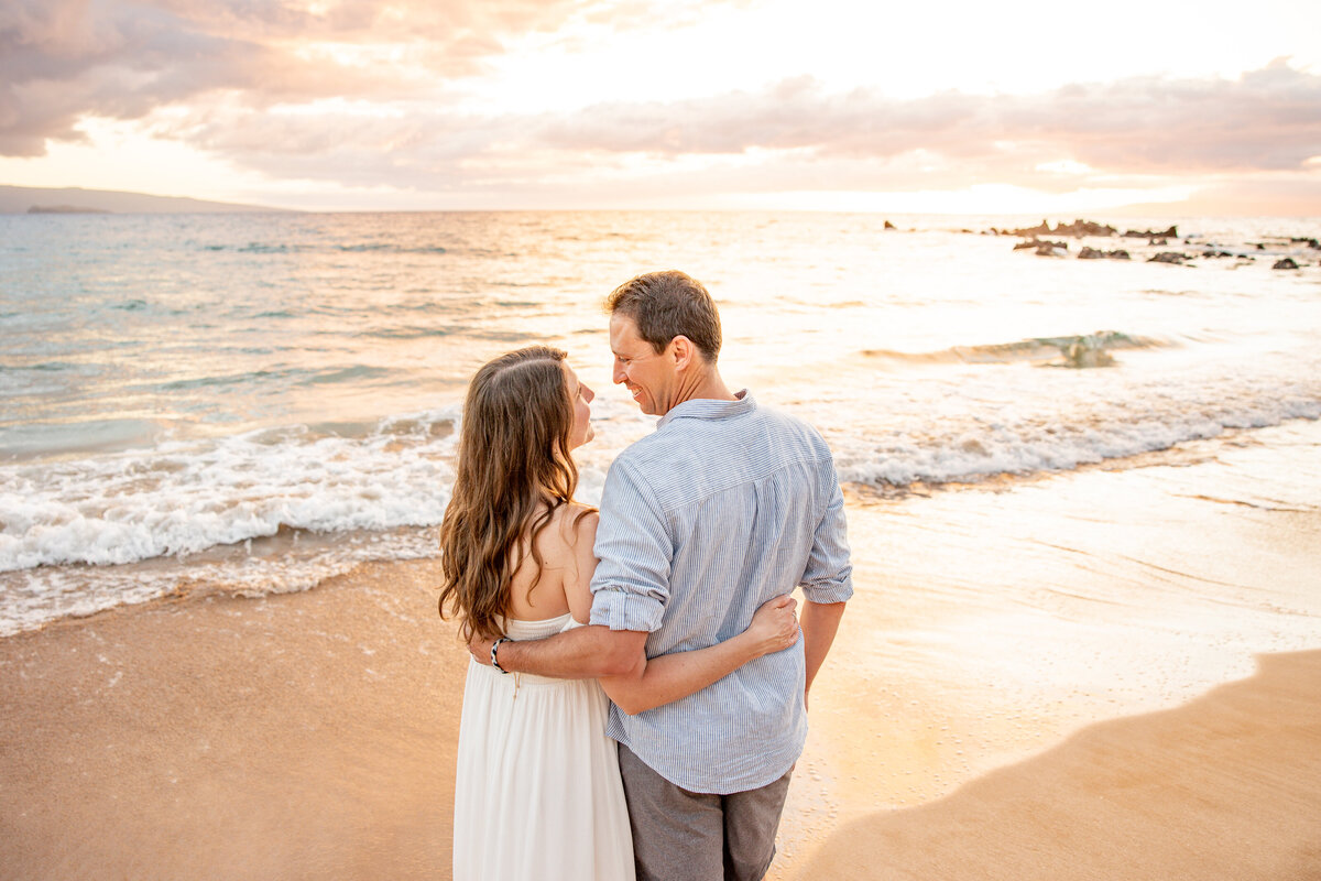 Maui Family Photographers capture couple embracing at sunset during family photos at beach in Maui