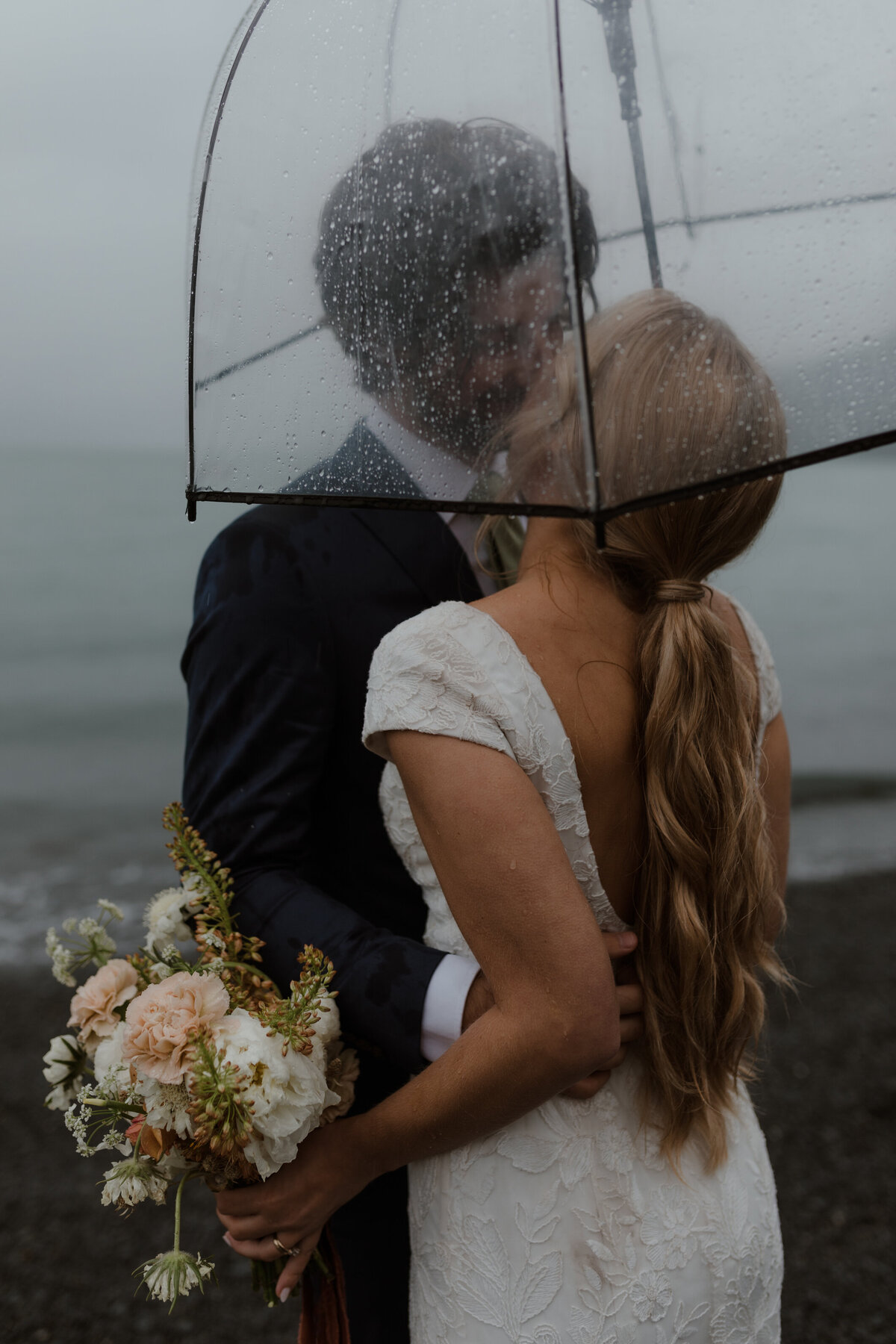 Wedding couple kissing under umbrella