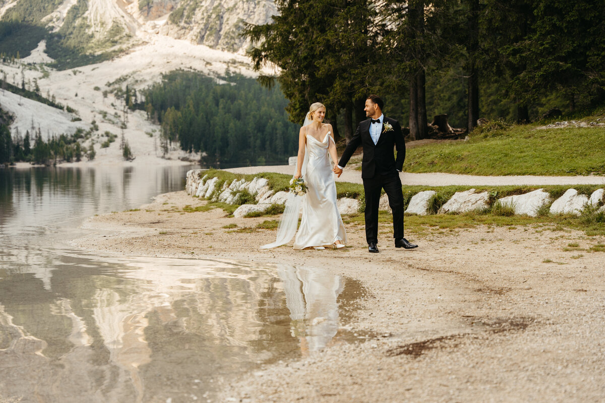 Couple walking by Lago di Braies with mountains behind