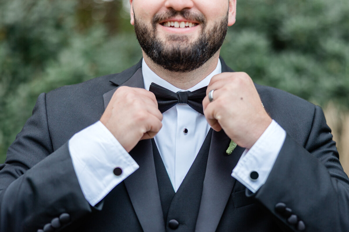 A groom straightens his bow tie for his luxurious black tie wedding
