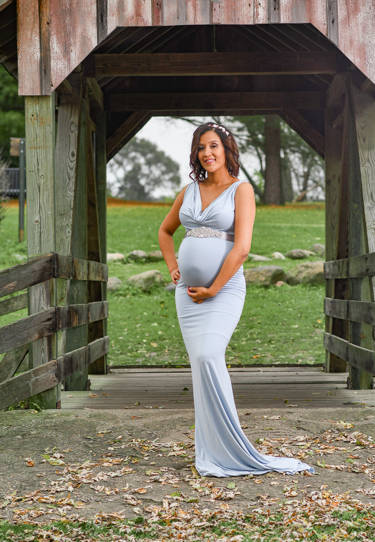 Pregnant woman in a long maternity gown photographed at a park on a covered bridge in Beloit, Wisconsin