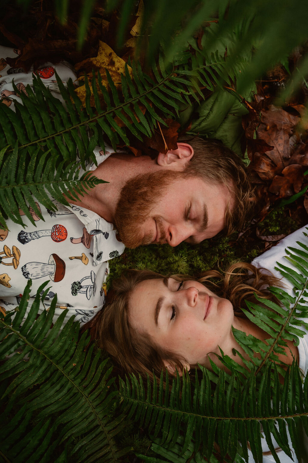 couple laying on forest floor in peace with ferns