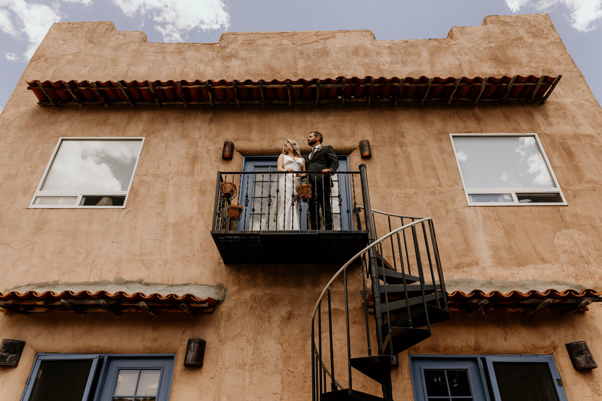 bride and groom standing on a balcony together on a southwestern adobe home