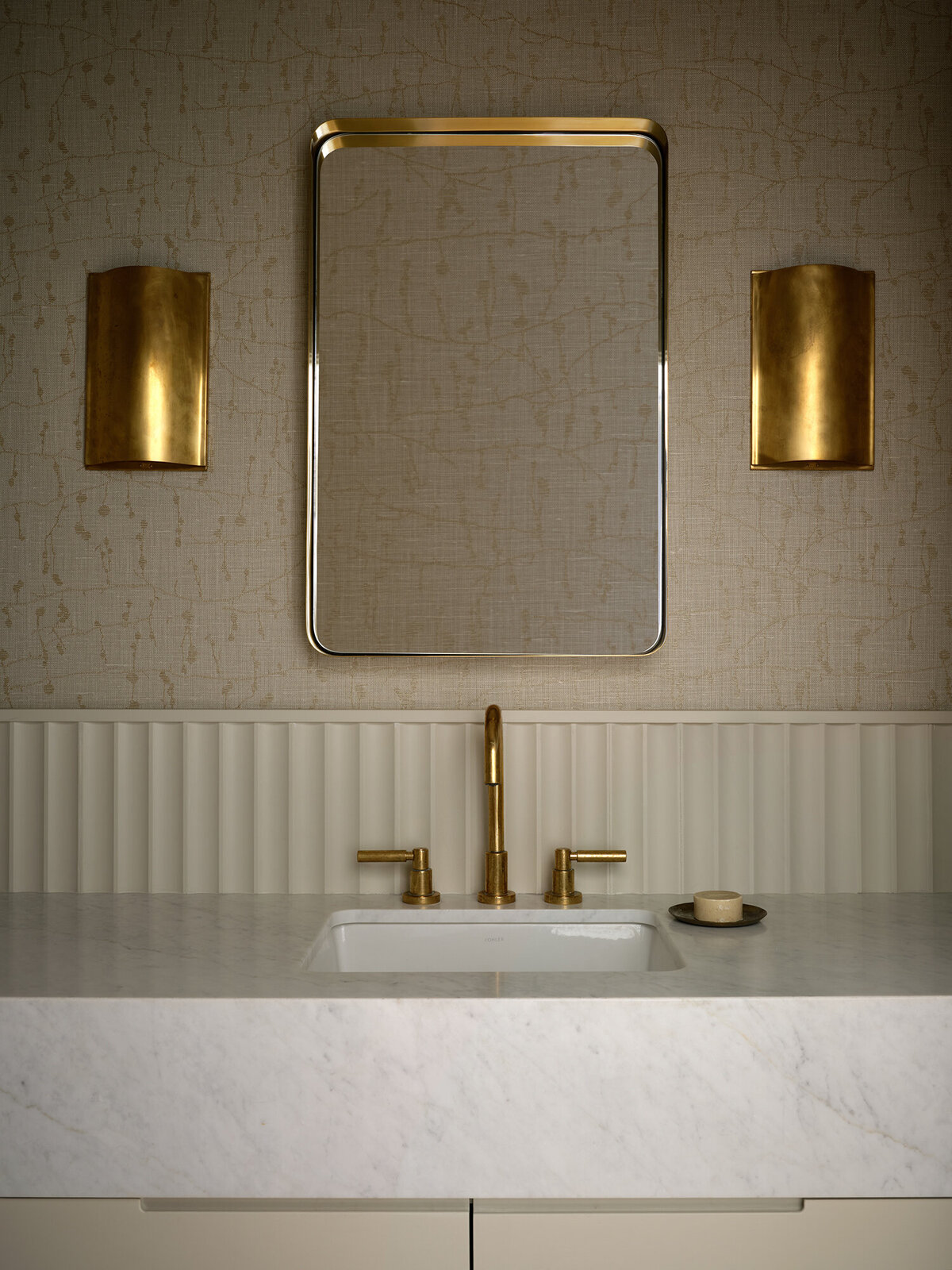 embroidered-wallpaper-warm-cozy-bathroom-powder-room-brass-kelly-wearstler-sconces-fluted-backsplash-carrara-marble-countertop-vanity-brass-faucet-austin-design-house-franc