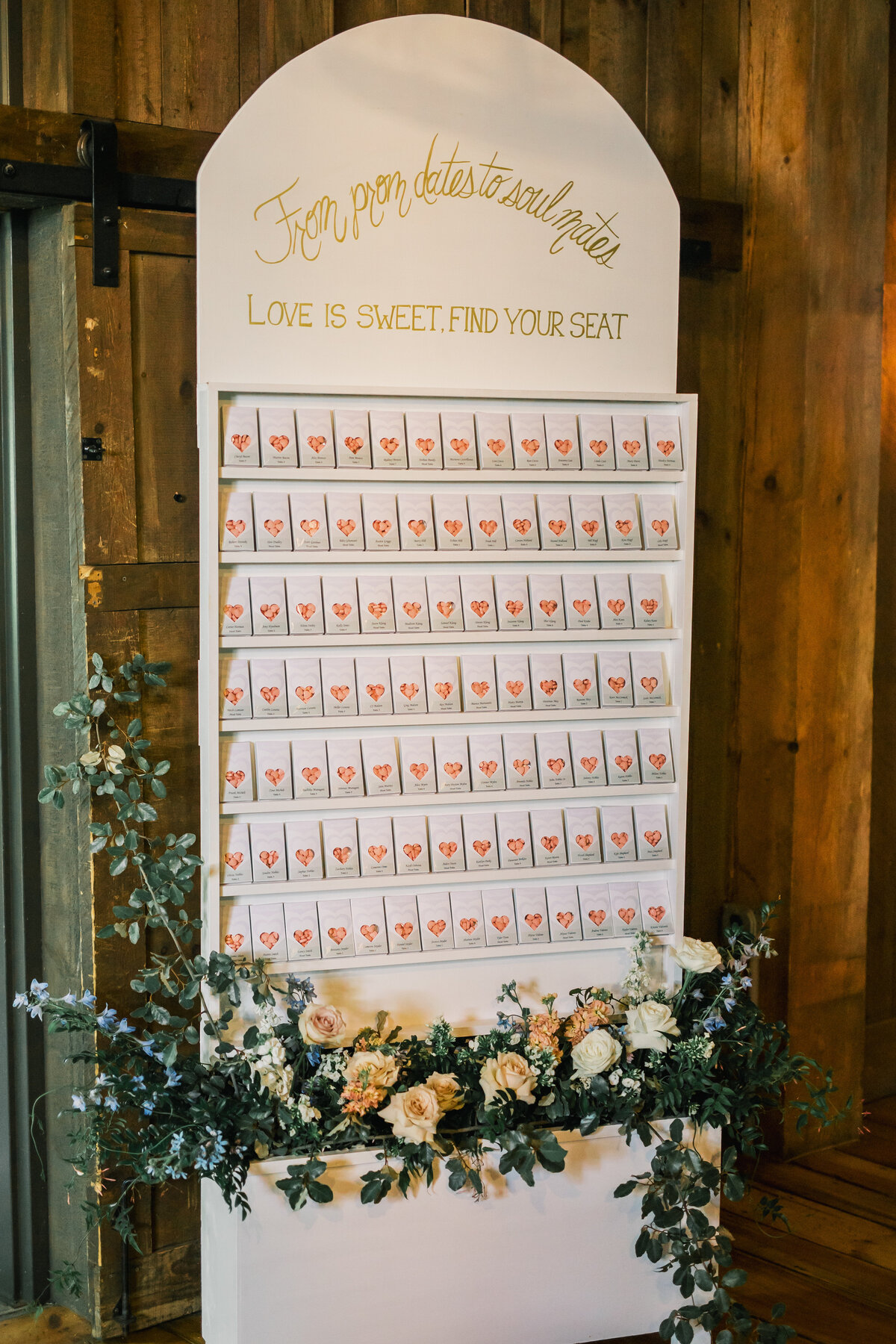 Custom escort card seating display with floral arrangements and signage reading 'Love is Sweet, Find Your Seat' at a wedding reception at Old Edwards Inn in Highlands, North Carolina.