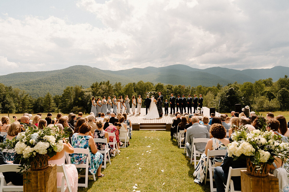 A picturesque Vermont summer wedding outside with the bride and groom at the alter and guests seated to watch the ceremony.