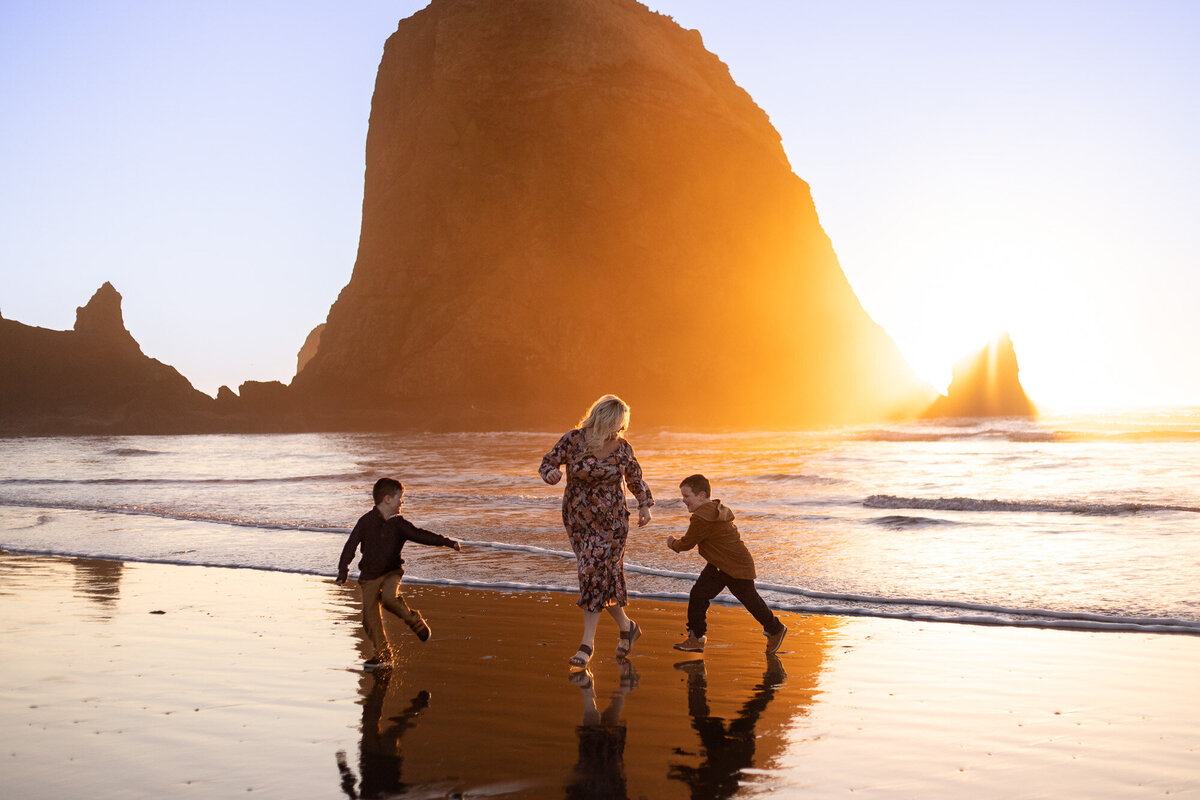 Mom and sons running on the Oregon Coast at sunset.