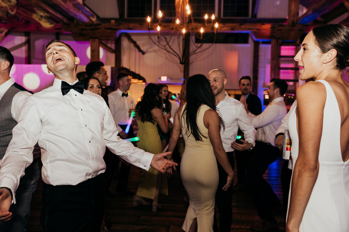 a bride and groom dancing with their guests at their wedding reception wtih pink and purple lighting at Willowbrook wedding venue