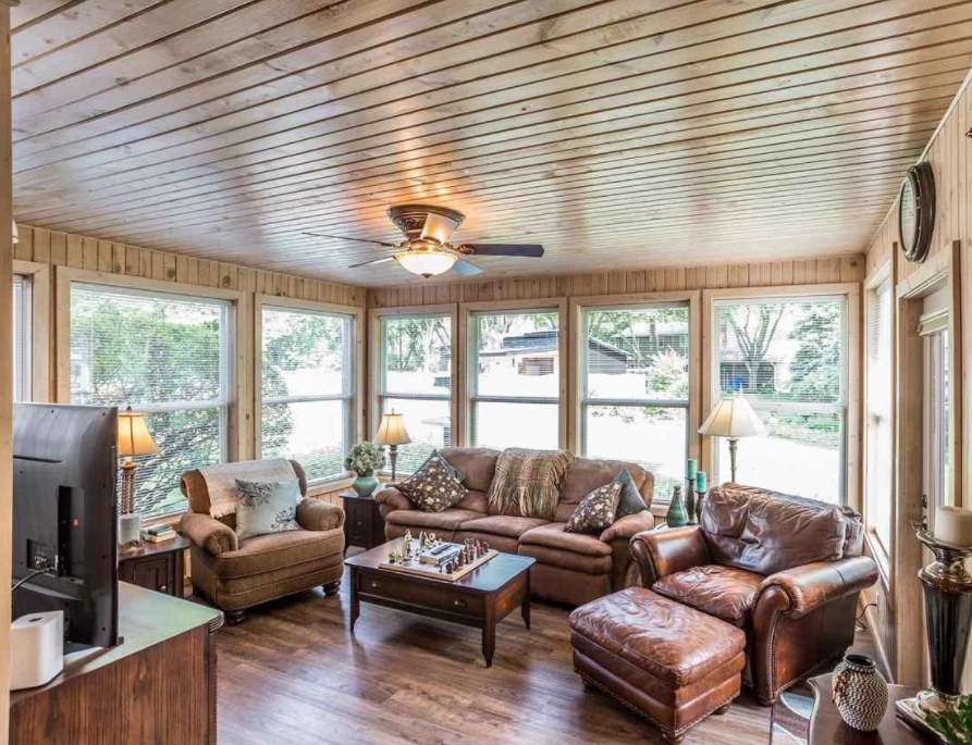 A sunroom with brown furniture and wood panelling