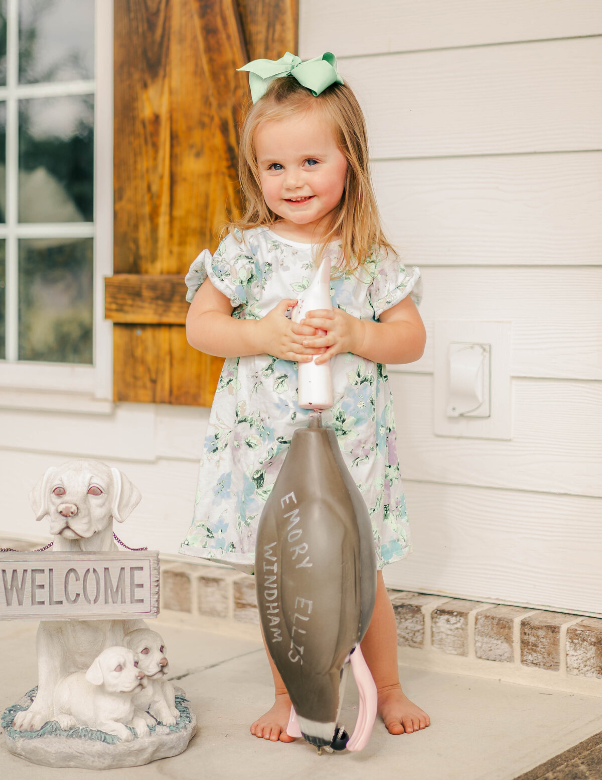 Smiling toddler girl holding the duck that will reveal the baby's gender at this gender reveal