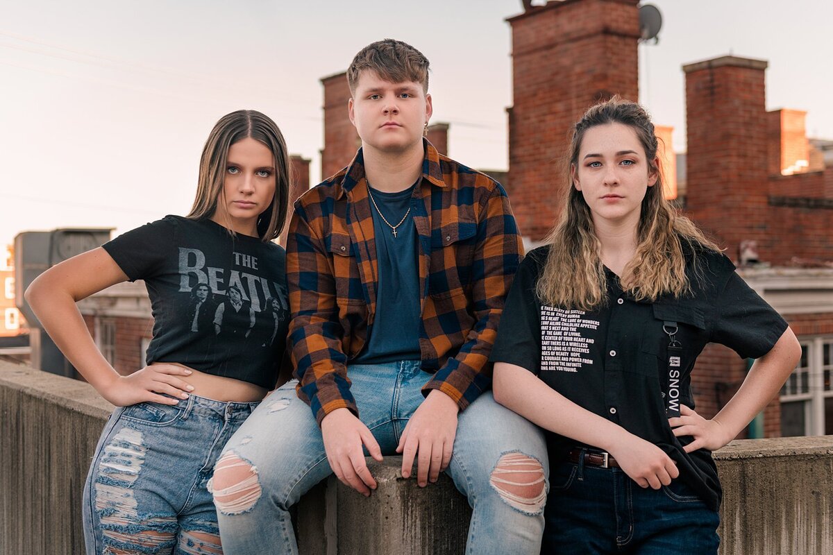 2 senior girls 1 senior guy sitting on wall on roof of parking garage