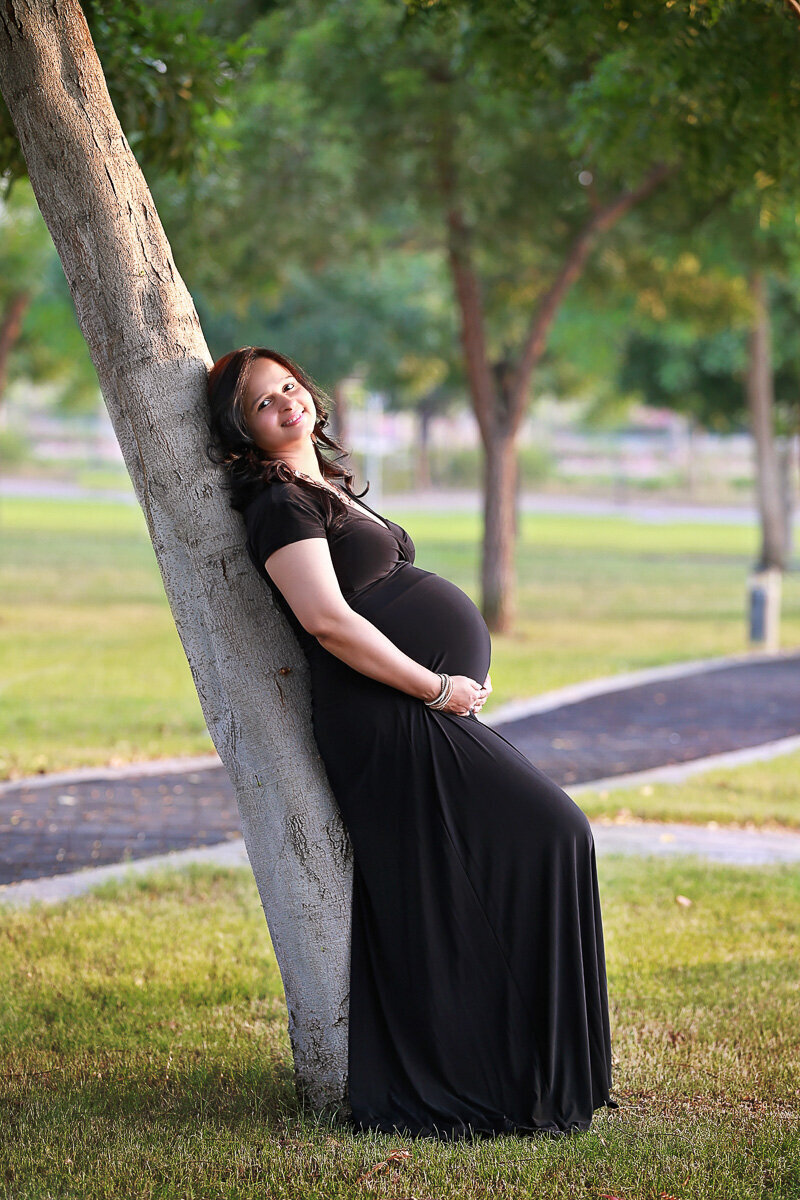 Pregnant mama in the black long dress leaning on the tree in Victoria British Columbia