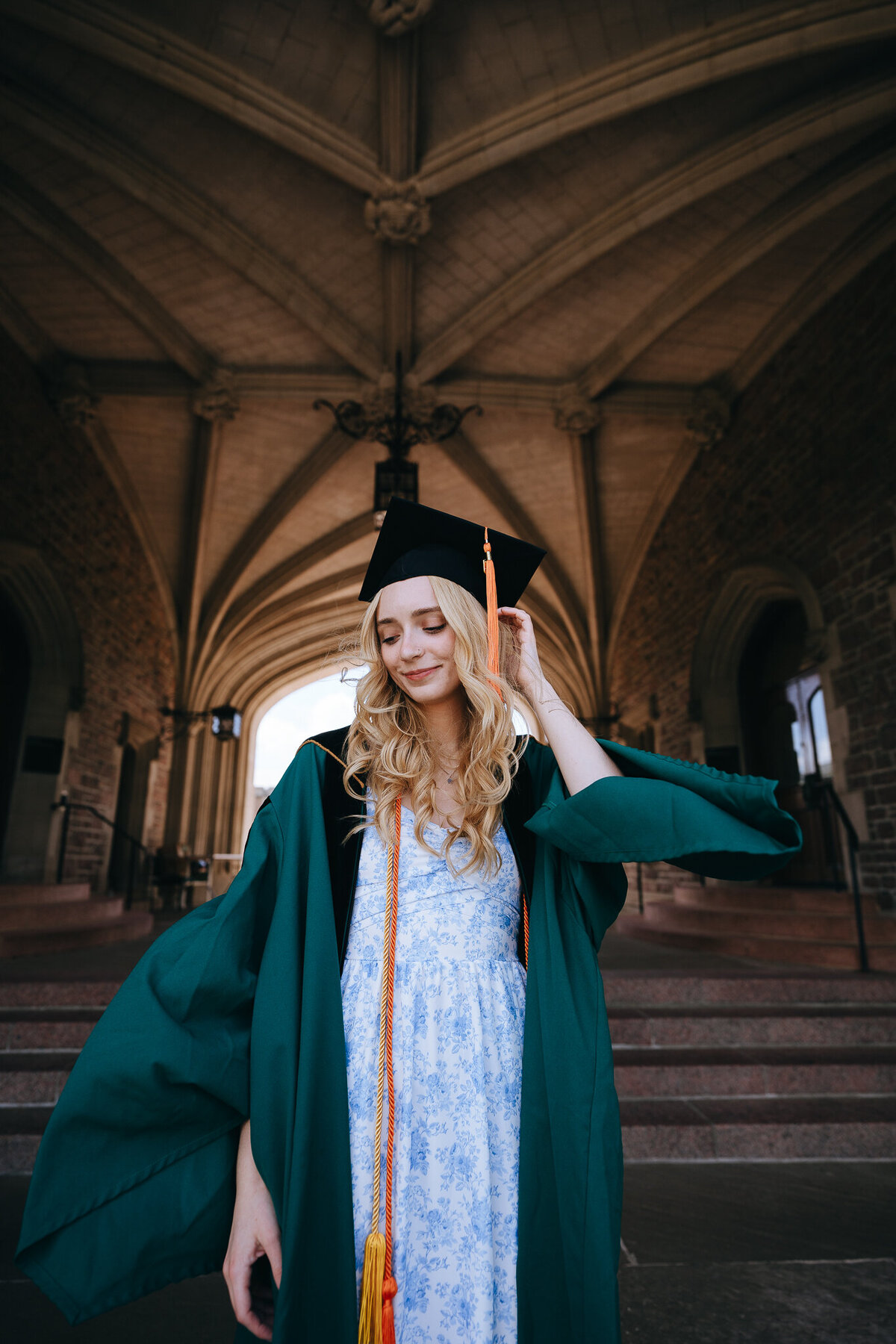 portrait of washu grad in regalia standing under brookings hall