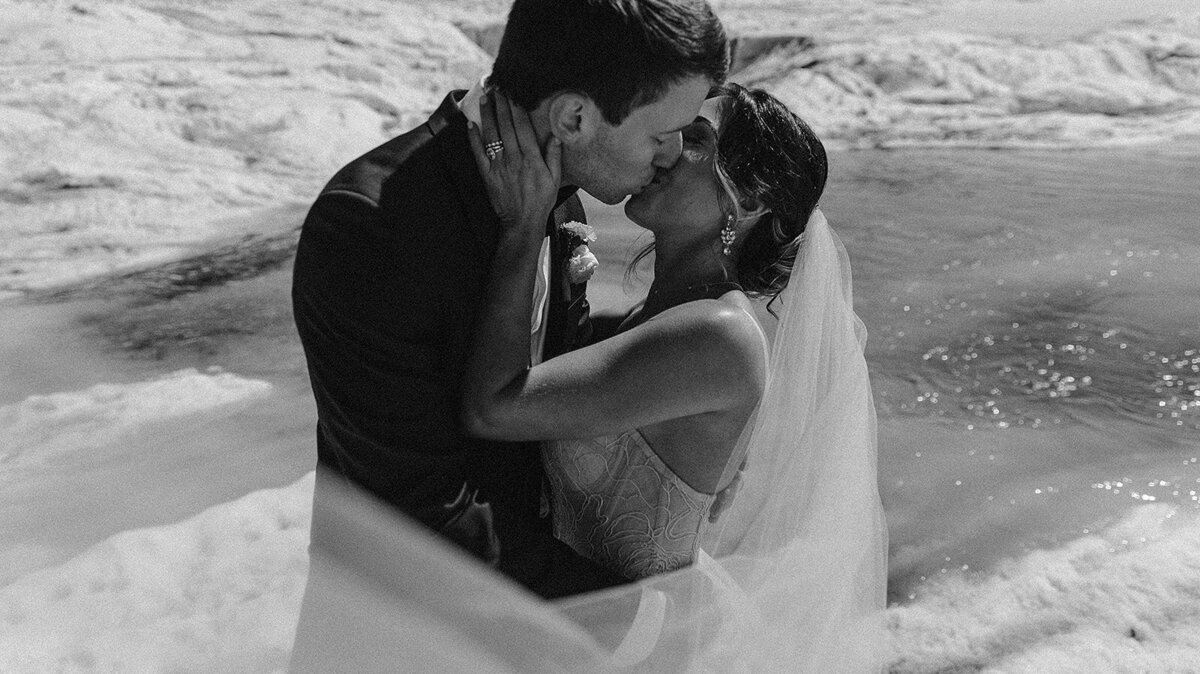 black and white image bride and groom sitting on beach