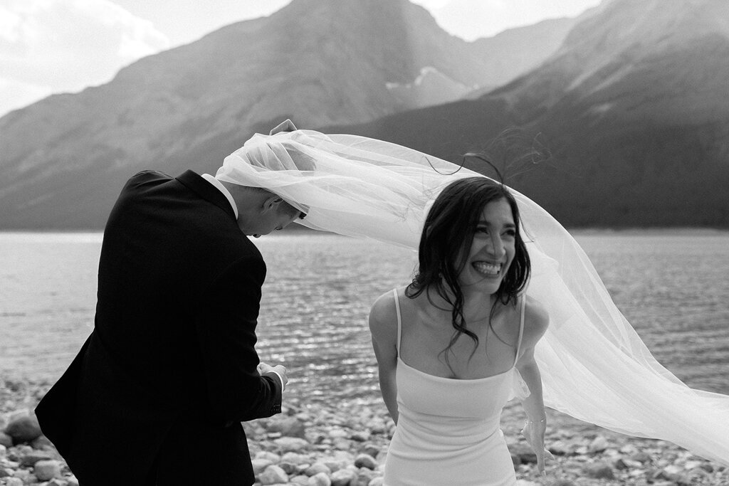 Fun wedding moment, brides veil blowing onto groom, by Court Amber Photography, joyful and adventurous wedding photographer in Calgary, Alberta. Featured on the Bronte Bride Vendor Guide.