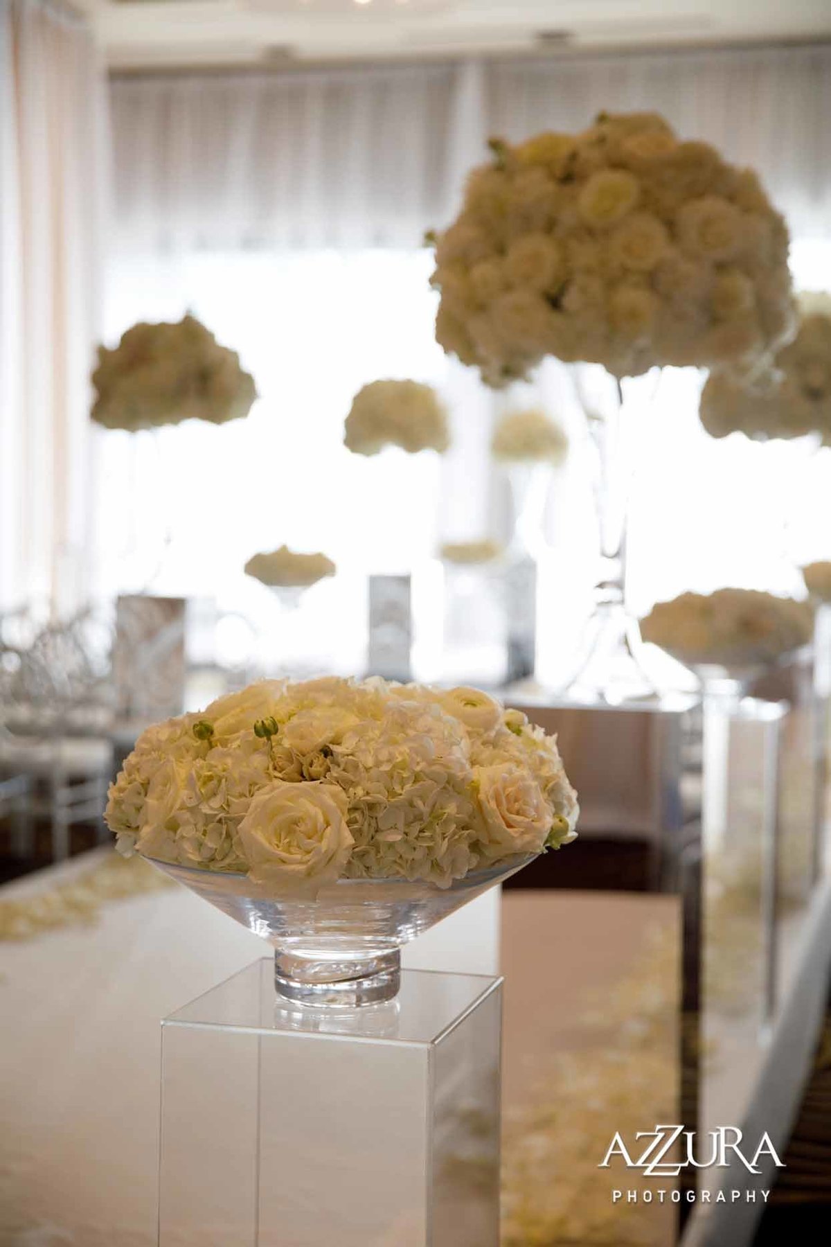 Wedding ceremony aisle of white flowers on top of clear lucite pedestals