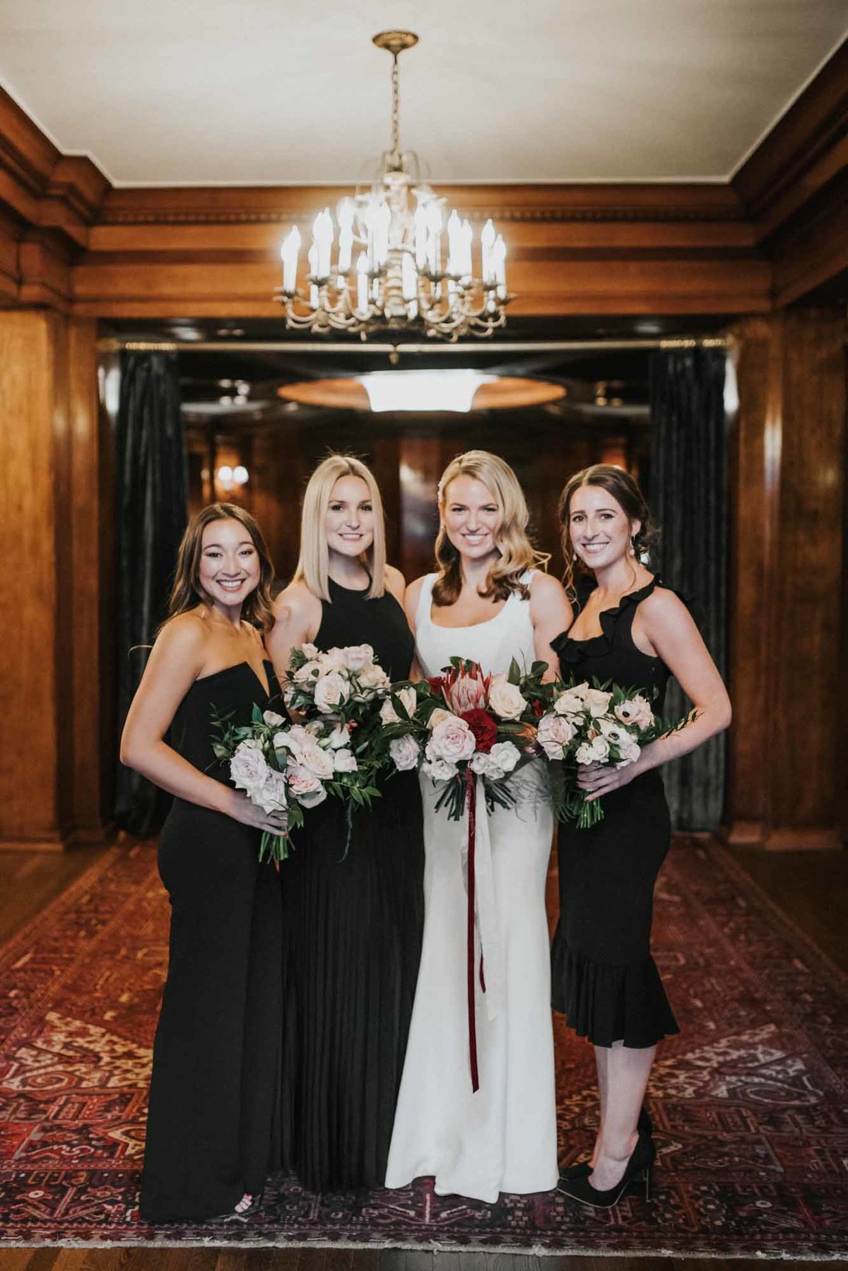 bride and bride's maids in black dresses with winter bouquets in red and white